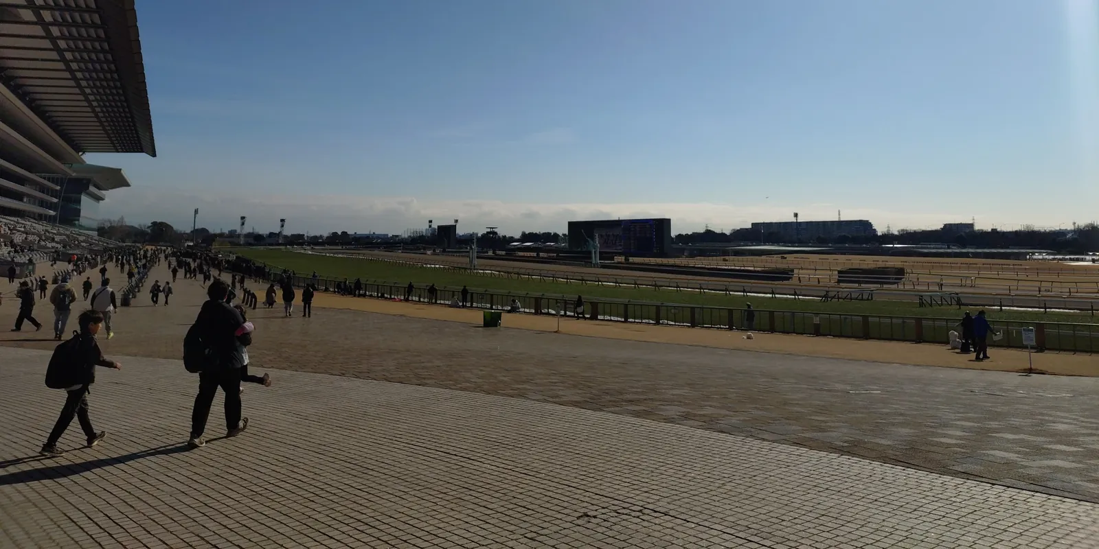 晴れた冬の日の東京競馬場。左にスタンド、手前に広場、奥にコースと大型ビジョン